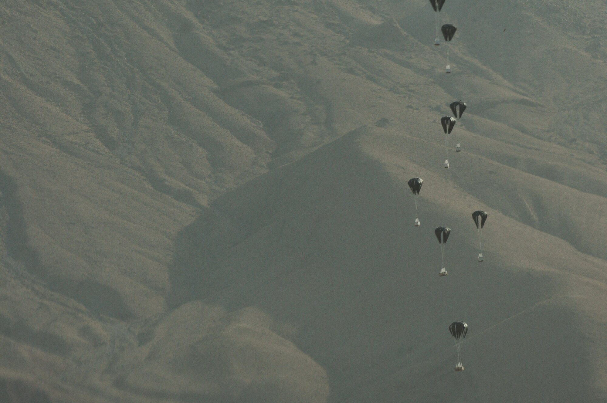 BAGRAM AIRFIELD, Afghanistan -- Pallets of much-needed supplies parachute down to a forward operating base in Oruzgan Province, Afghanistan, June 22. Two C-130 Hercules aircraft, one from the Alaska Air National Guard and one from the New York Air National Guard, performed the joint airdrop. Airdrops help mitigate the danger of transporting supplies via convoy. (U.S. Air Force photo by Senior Airman Krista Rose.)