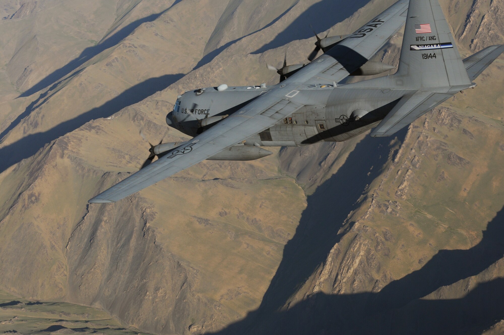 BAGRAM AIRFIELD, Afghanistan -- A C-130 Hercules from the New York Air National Guard flies over mountainous Afghan terrain on its way to delivering much-needed supplies to a forward operating base in Oruzgan Province, Afghanistan, June 22. The New York ANG C-130 flew the airdrop mission in conjunction with another C-130 from the Alaska ANG. Airdrops help mitigate the danger of transporting supplies via convoy. (U.S. Air Force photo by Senior Airman Krista Rose.)