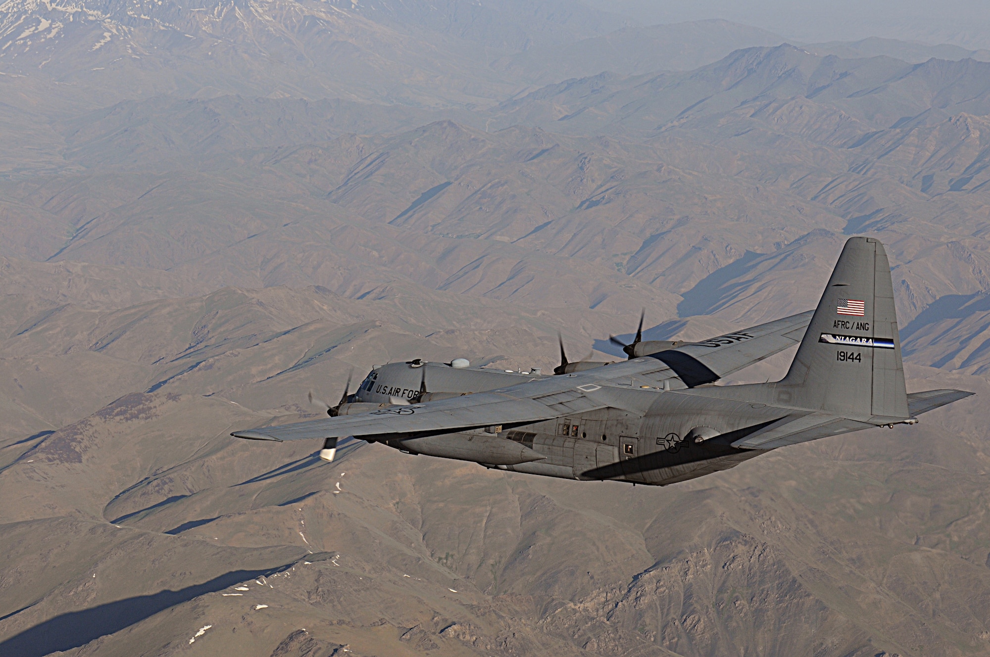 BAGRAM AIRFIELD, Afghanistan -- A C-130 Hercules from the New York Air National Guard flies over rugged Afghan landscape on its way to delivering much-needed supplies to a forward operating base in Oruzgan Province, Afghanistan, June 22. The New York ANG C-130 flew the airdrop mission in conjunction with another C-130 from the Alaska ANG. Airdrops help mitigate the danger of transporting supplies via convoy. (U.S. Air Force photo by Senior Airman Krista Rose.)