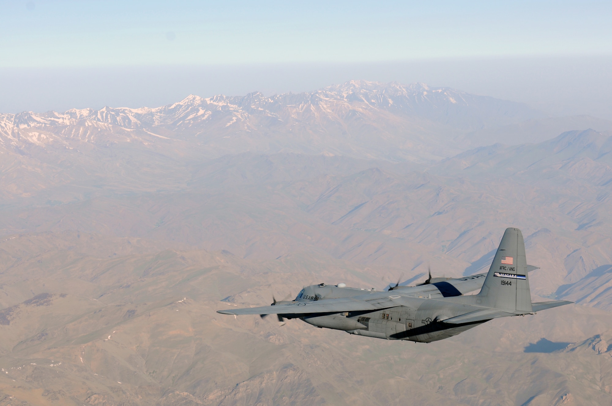 BAGRAM AIRFIELD, Afghanistan -- A C-130 Hercules from the New York Air National Guard flies over mountainous Afghan terrain on its way to delivering much-needed supplies to a forward operating base in Oruzgan Province, Afghanistan, June 22. The New York ANG C-130 flew the airdrop mission in conjunction with another C-130 from the Alaska ANG. Airdrops help mitigate the danger of transporting supplies via convoy. (U.S. Air Force photo by Senior Airman Krista Rose.)