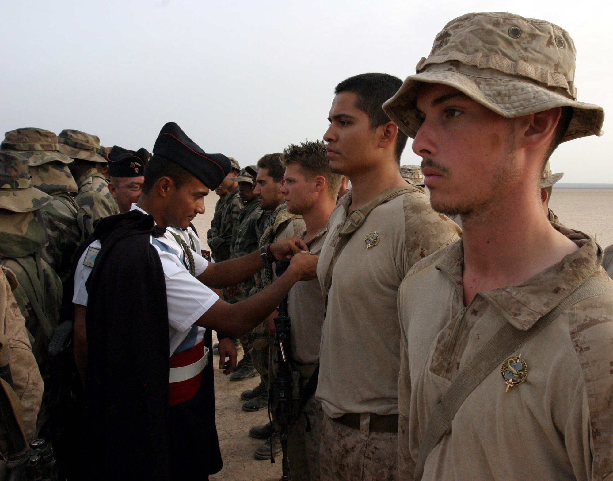 GRAND BARA, Djibouti -- U.S. Marines assigned to the 13th Marine Expeditionary Unit at Camp Lemonnier, Djibouti, are awarded a numbered pin for completing the French Army 5th French Marine Regiment Desert Combat Training course in Djibouti on June 9. The 10-day course provided nearly 120 French and 40 U.S. servicemembers with a basic knowledge of field tactics and survival techniques to use within a desert environment. (U.S. Marine Corps photo by Lance Corporal Massimo Selim)