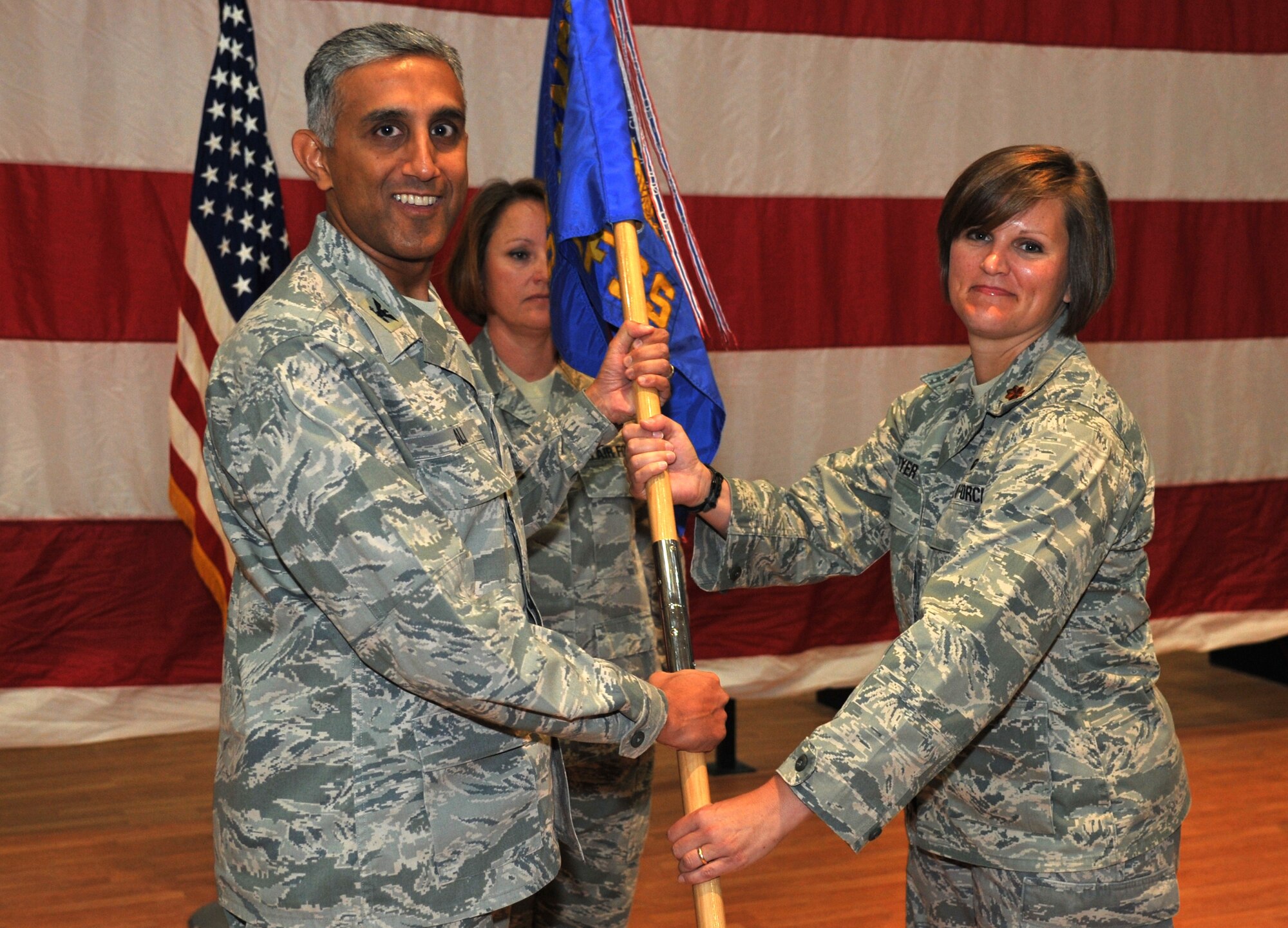Col. Rizwan Ali, 386th Expeditionary Mission Support Group commander, left, passes the 386th Expeditionary Force Support Squadron guide-on to Major Heather K. Meyer during a change of command ceremony June 23 at an undisclosed location in Southwest Asia. Major Meyer assumed command of the 386th EFSS from Major Rosalie A. Duarte. (U.S. Air Force photo by Master Sgt. Carlotta Holley)