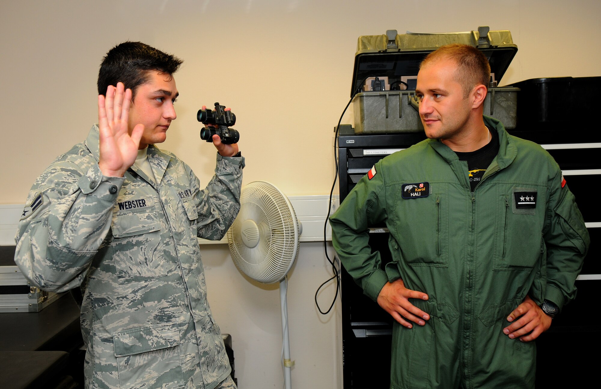 SPANGDAHLEM AIR BASE, Germany – Airman 1st Class William Webster, 52nd Operations Support Squadron aircrew flight equipment apprentice, demonstrates to Polish air force 1st Lt. Karol Hali the angle of view provided by nightvision goggles here June 21. Poland’s air force visited the 52nd Fighter Wing to build community relations and learn about the base’s daily flight support operations. (U.S. Air Force photo/Airman 1st Class Dillon Davis)