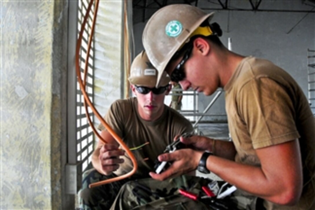 U.S. Navy Seaman Rodney Peters (right) and Petty Officer 3rd Class Jared Campos wire an outlet during an engineering civil action project as a part of Pacific Partnership in Dili, Timor-Leste, on June 17, 2011.  Peters, a construction electrician constructionman, and Campos, a steel worker, are assigned to Naval Mobile Construction Battalion 133.  