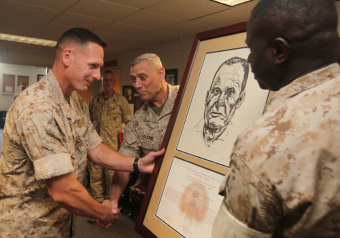 LtCol. Jason Waldron, executive officer for the 24th Marine Expeditionary Unit, receives a plaque June 23, 2001, in recognition of 24th MEU being awarded the Lieutenant General "Chesty" Puller Outstanding Leadership Award from the commanding general and sergeant major of II Marine Expeditionary Force, Lt. Gen. John M. Paxton and Sgt. Maj. Carl Green (right.)  24th MEU's command element received the award in the small unit category for sustained excellence in maintaining high levels of readiness and force preservation during their training cycle in 2009 and through their deployment in 2010.