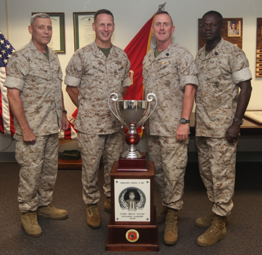 (From left to right)  Lt. Gen. John Paxton, commanding general, II Marine Expeditionary Force, Lt. Col. Jason Waldron, executive officer, 24th Marine Expeditionary Unit,  Sgt. Maj. John McGovern, 24th MEU Sgt. Maj., and Sgt. Maj. Carl Green, II MEF Sgt. Maj., pose for a photo in front of the Lieutenant General "Chesty" Puller Oustanding Leadership Award June 23, 2011, at the 24th MEU headquarters building after the award was presented to the 24th MEU.  The award was given to 24th MEU to recognize the unit's sustained excellence in all aspects of unit readiness.