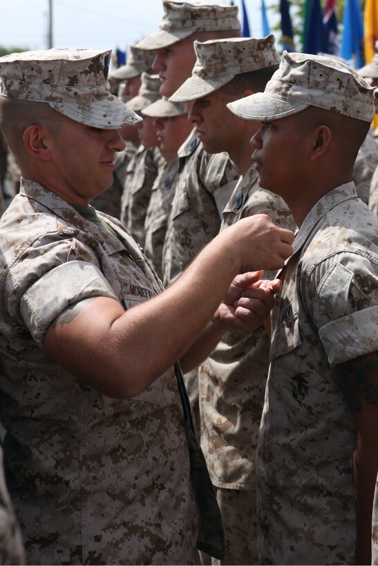 A Field Medical Training Battalion instructor pins a hospital corpsman's caduceus shield on his collar during the Field Medical Service Technician course graduation at Camp Pendleton, June 24.  The eight-week course at FMTB introduces hospital corpsmen to daily Marine Corps operations through hands-on training and interaction with Marines.  The students learn about customs and courtesies, weapons procedures, basic fundamentals of marksmanship, basic infantry skills and a variety of medical techniques and skills to enhance their field medical capabilities.