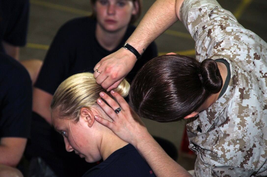 Rachael Weatherford, a 20-year-old graduate of Minnewaska High School, watches Cpl. Rebecca Carlson, 22, from Hastings, Minn., put up Sarah Belden's hair with a sock-bun while attending a Recruiting Station Twin Cities female pool function June 24-25. Women are usually taught this hygiene technique by drill instructors once they arrive at boot camp. Belden, 18, from Austin, Minn., ships off to Parris Island, S.C., on July 11. Weatherford was recruited out of the Buffalo, Minn., office. For additional imagery from the event, visit www.facebook.com/rstwincities.