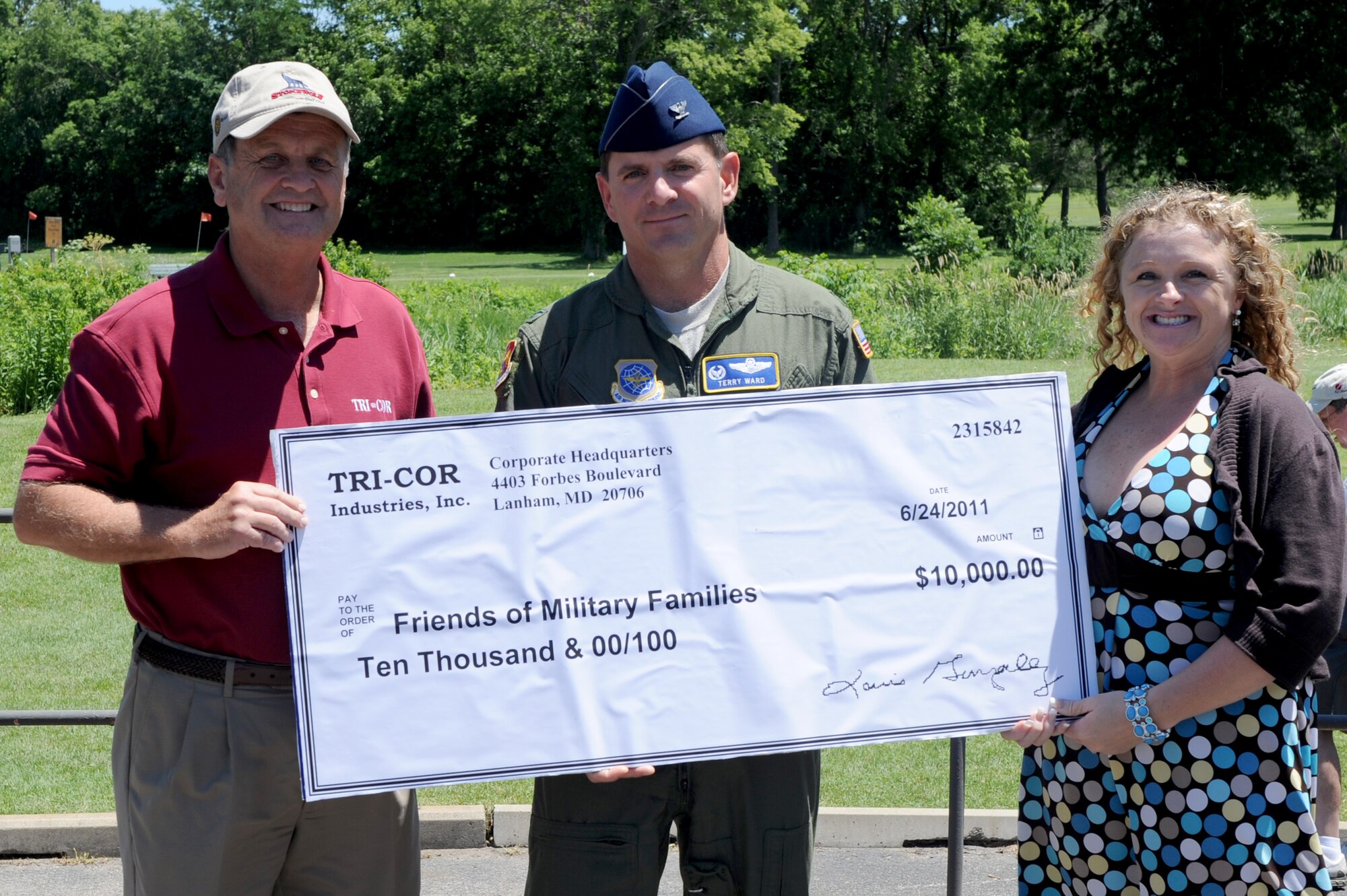 SCOTT AIR FORCE BASE, Ill. -- Left, Scott Parker, Tri-Cor Industries director of operations, presents a donation check to Col. Terry Ward, 375th Operations Group commander, and Lona Berndt, Friends of Military Families treasurer, to help fund the private organization’s efforts to assist military families in need during deployments or financial hardships as part of an annual benefit golf tournament June 24. (U.S. Air Force Photo/ Staff Sgt. Brian J. Valencia)