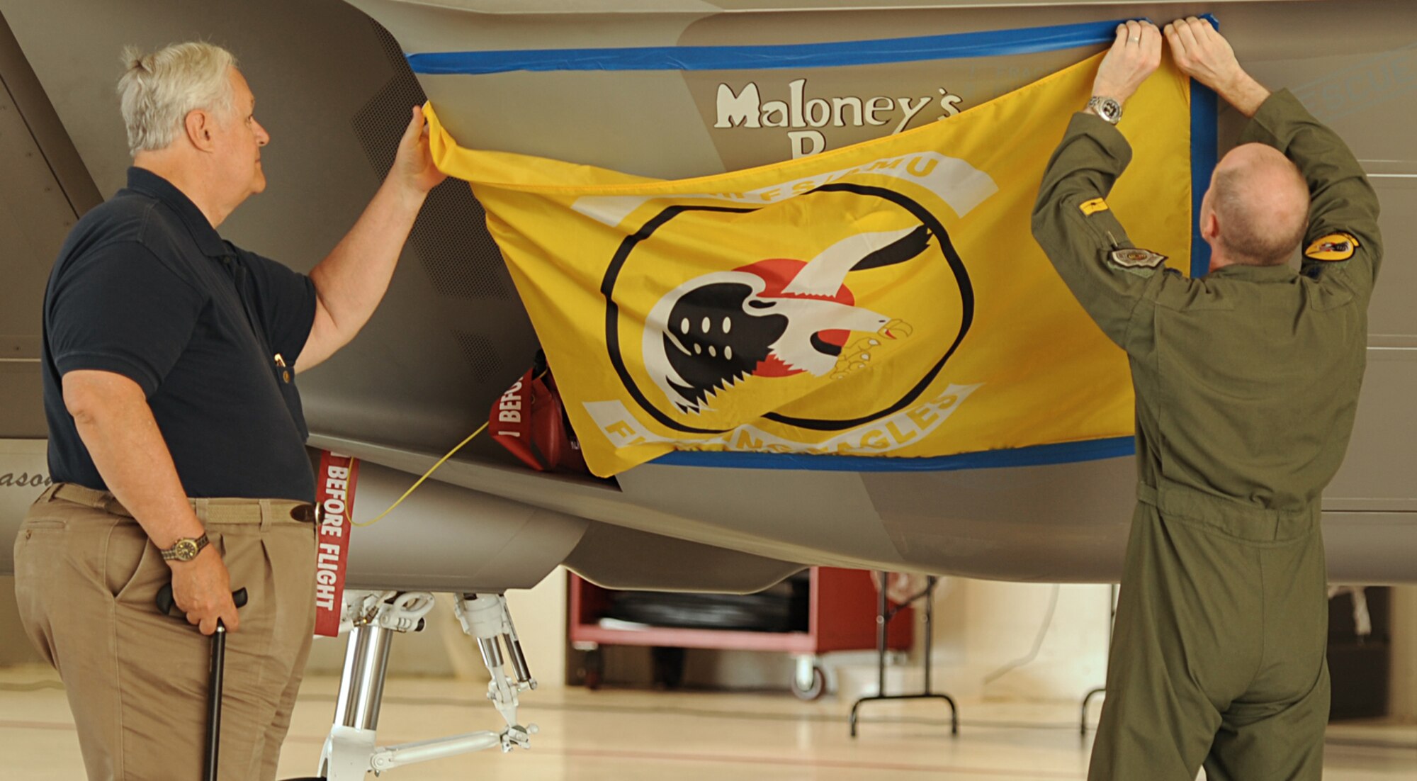 Rick Maloney, son of Maj. Thomas E. Maloney, a World War II Ace, and Lt. Col. Jason Hinds, 27th Fighter Squadron director of operations, unveil artwork displayed on the body of an F-22 Raptor at Langley Air Force Base, Va., June 24, 2011. The artwork was painted on the Raptor in honor of Maloney, the 27th Fighter Squadron’s highest scoring Ace of World War II. (U.S. Air Force photo by Airman 1st Class Teresa Cleveland/Released)