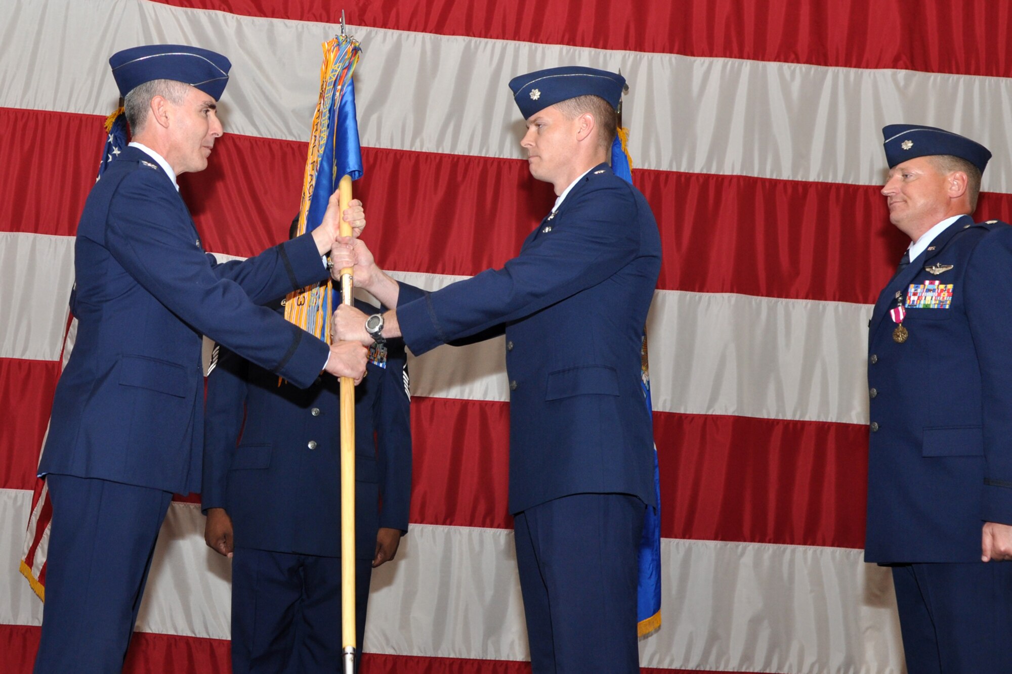 With the passing of the guidon from Colonel John M. Vitacca, commander, 2nd Operations Group, Lt. Col. W. Heath Wharton, accepts command of the 11th Bomb Squadron during the change of command ceremony held Thursday, June 23, 2011, in Hoban Hall at Barksdale Air Force Base, La. Colonel Wharton took the reins of the 11th BS from Lt. Col. Kieran T. Denehan, (far right) who is headed to California for his next assignment. The 11th BS works alongside the 93rd Bomb Squadron as partners in the B-52 Formal Training Unit at Barksdale, which trains flight crews for the B-52 Stratofortress. To accomplish this task of forging new aviators into Combat Ready B-52 crewmembers takes the work of both AF Reserve and Active Duty Members. (U.S. Air Force photo/Tech. Sgt. Jeff Walston)