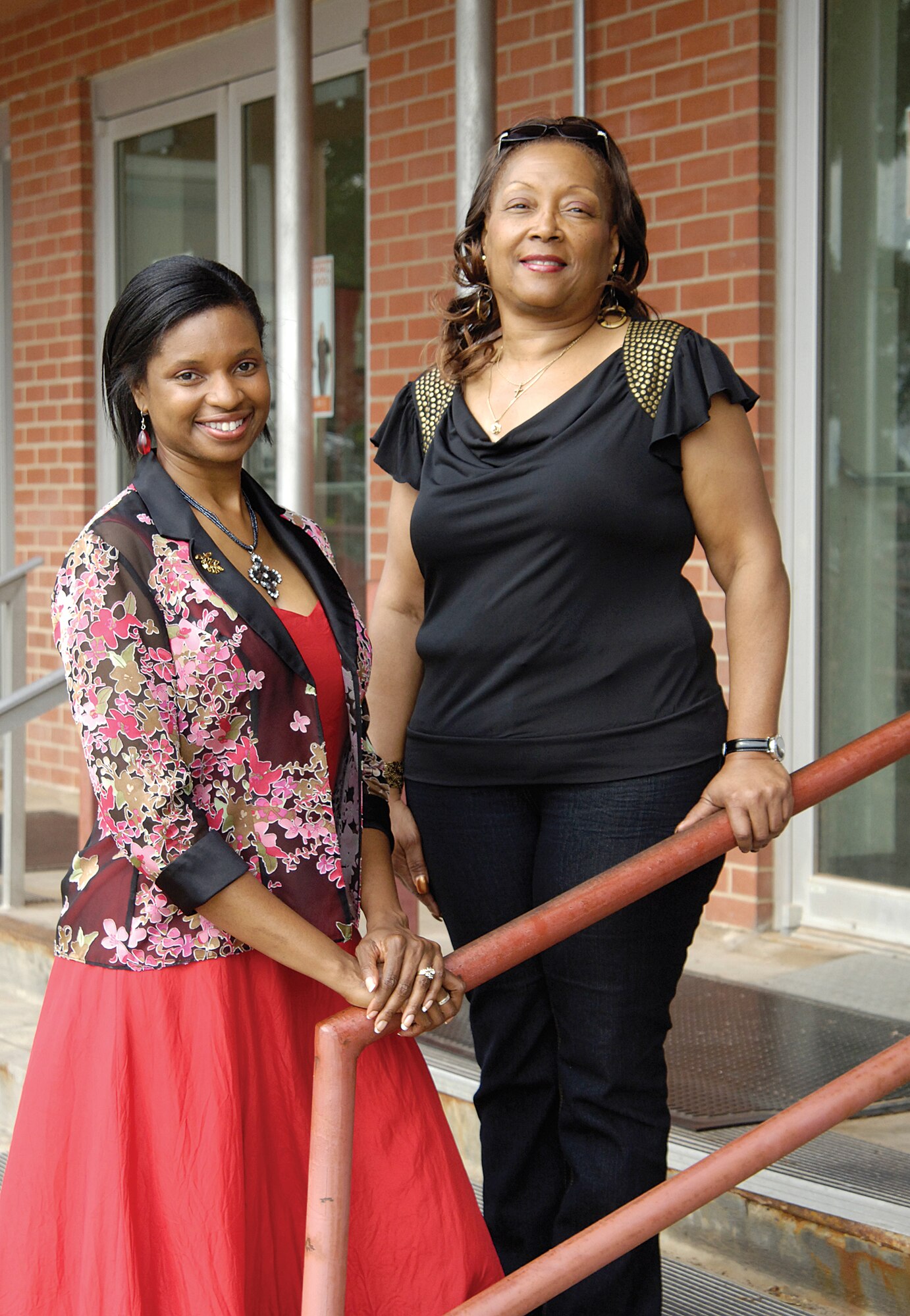 A handrail similar to this one outside Bldg. 3001 entrance door G will soon be installed on exit stairs outside door F, a welcome addition for employees Renita Gilliam, left, and Lavisa Purify of the 422nd Supply Chain Management Squadron. Coming down the handrail-less stairs during a fire drill, Ms. Purify fell and Ms. Gilliam reported the safety hazard.  The Voluntary Protection Program encourages such employee involvement and the Oklahoma City Air Logistics Center’s Combined Wing Staff Group, which includes the 448th SCMW, strives to keep safety a constant priority for its workforce. (Air Force photo by Margo Wright)