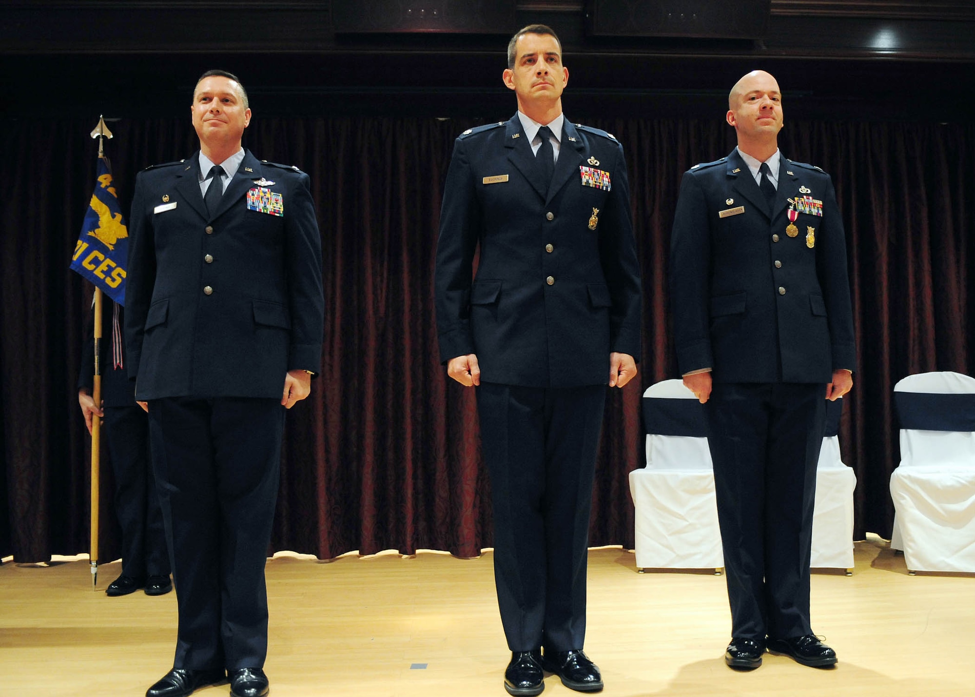 Colonel Johnathan Hughes, 421st Air Base Group commander, officiates the 421st Civil Engineer Squadron change of command ceremony, Lt. Col. Bradford Buckman, the new Civil Engineer Sqauadron Commander, and Lt. Col. Mark Laudenslager, the outbound commander, stand at the position of attention after passing the guidon during the Change of Command ceremony at the Menwith Hill Base Club, June 20, 2011.