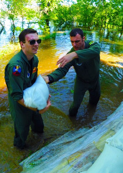 Burlington, N.D. -- 1st Lt. Devin Vitt(left) and Capt. Bryant Harrison, 23rd Bomb Squadron radar navigator and pilot respectively, help sandbag the home of Lt. Col. John Dawson, 5th Bomb Wing Inspector General, in Burlington, N.D. June 23, 2011. The Airmen are assigned to Minot Air Force Base, N.D. The Souris River, which begins in the Canadian province of Saskatchewan, is expected to inundate thousands of homes and businesses. (U.S. Air Force photo by Staff Sharida Jackson) (RELEASED)