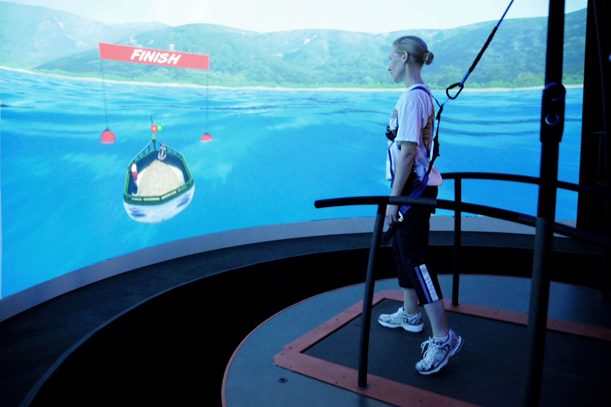Navy Lt. Cdr. Jena McLellan, a clinical trials coordinator with the National Intrepid Center of Excellence in Bethesda, Md., demonstrates the center’s Computer-Assisted Rehabilitation Environment, or CAREN, a virtual reality system to assess wounded warriors with traumatic brain injury or post-traumatic stress.  (NICoE photo/Linsey Pizzulo)