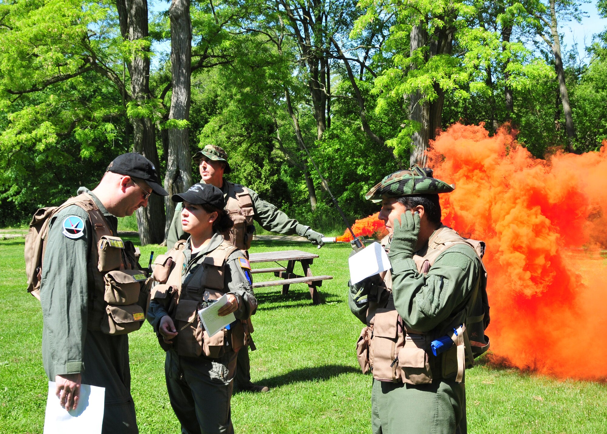 MILWAUKEE--An aircrew member from the 128th Air Refueling Wing's Operations Squadron signals with orange smoke while another aircrew member communicates with the pilot of a U.S. Coast Guard HH-65 Dolphin Search and Rescue helicopter during an annual training event on Saturday, June 25, 2011.  The training event reinforced survival techniques that all Air Force aircrew personnel learn as part of their career field.  (U.S. Air Force photo by Master Sgt. Kenneth Pagel / Released)