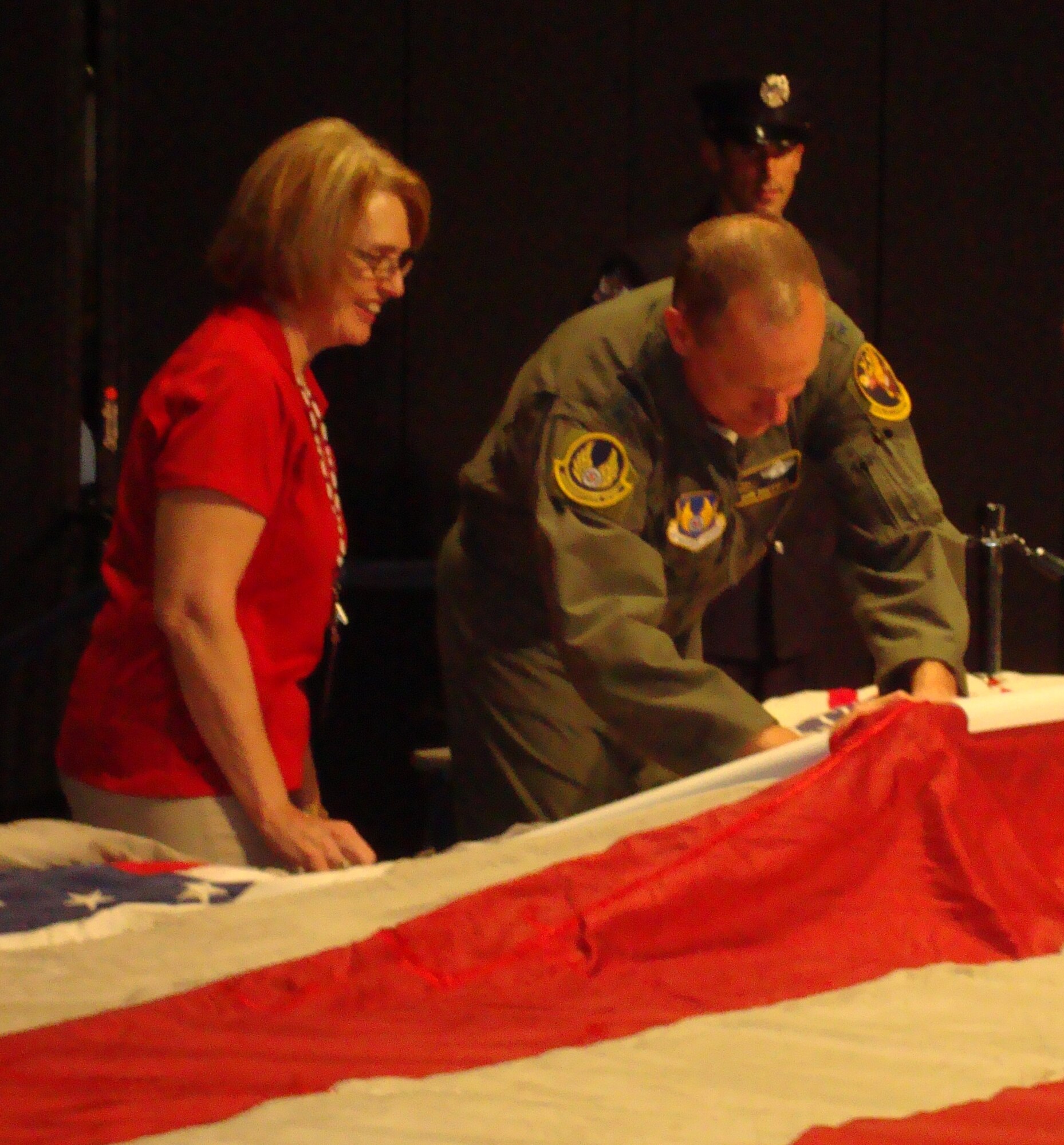 Air Force Materiel Commander Gen. Donald Hoffman sews a stitch into the National 9/11 Flag during a ceremony at the National Museum of the U,S. Air Force prior to the AFMC Freedom's Call Tattoo June 24, 2011. The flag was flying near the World Trade Center in New York City on Sept. 11, 2001, and was all but destoryed by the terrorist attacks. It is being stitched back togehter while on a 50-state tour. Stitches are added by military members, veterans, first responders and a vareity of community service heroes. The Ohio patch to the flag came from a flag flown outside AFMC Headquarters. Sponsored by the New York Says Thank You Foundation, the flag will eventually be displayed at the National 9/11 Museum to be built at the World Trade Center site. Assisting General Hoffman was Carolyn Deters of the foundation. (U.S. Air Force photo/Ron Fry)