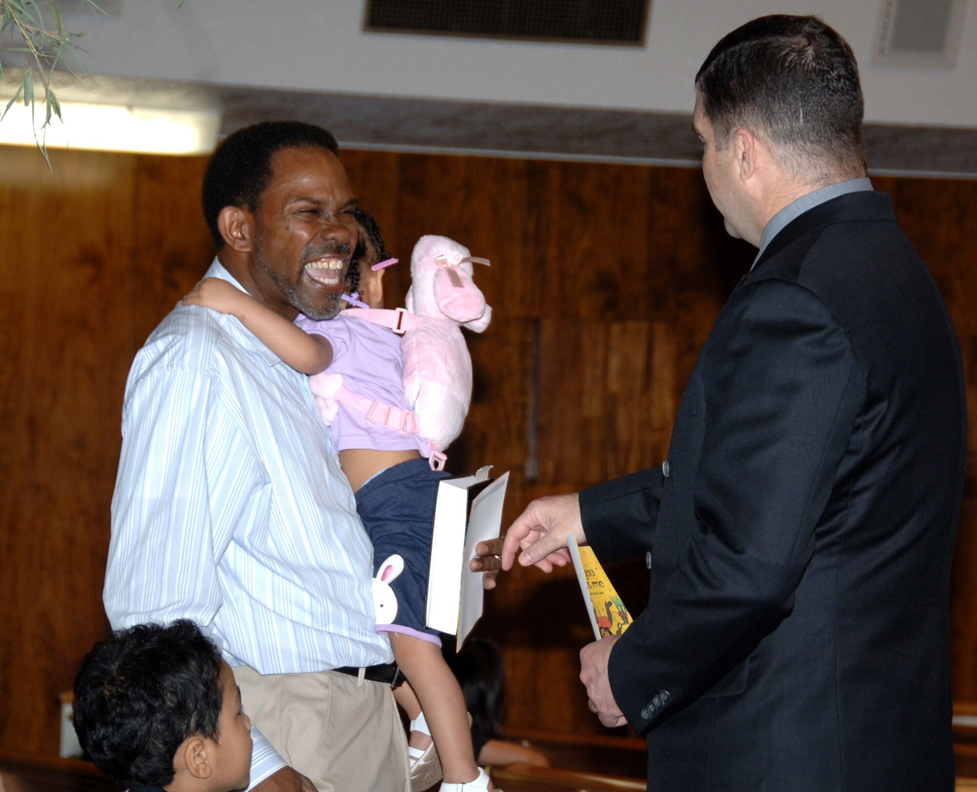 YOKOTA AIR BASE, Japan -- Capt. David Horton (right), 374th Airlift Wing chaplain, welcomes Jonathan Richardson and his grandchildren to the Traditional Chapel for Sunday worship service at Yokota Air Base, Japan, June 26, 2011. As a chaplain, Captain Horton is responsible for providing members of the Yokota community with the opportunity to practice the religion of their choice. (U.S. Air Force photo/Airman 1st Class Katrina R. Menchaca)