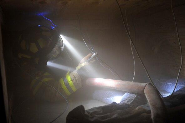 Matthew Croteau, firefighter with the 55th Civil Engineering Squadron, clips wires during the Surviving the Fire Ground, Fire Fighter/Fire Officer and Command Preparedness exercise inside building 163 on Offutt Air Force Base, Neb., June 22. Mr. Crouteau was one of 48 firefighters who participated in this training exercise. U.S. Air Force Photo by Charles Haymond/Released 