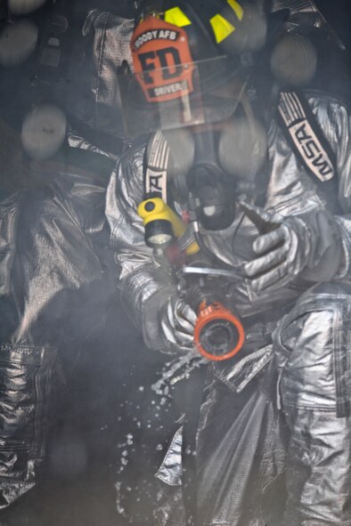 A firefighter from the 23rd Civil Engineer Squadron shuts off his hose after extinguishing a fire and pushing away smoke during training at Moody Air Force Base, Ga., June 24, 2011. During the training, firefighters were evaluated by senior members on using proper methods to put out a fire. (U.S. Air Force photo by Airman 1st Class Nicholas Benroth/Released)