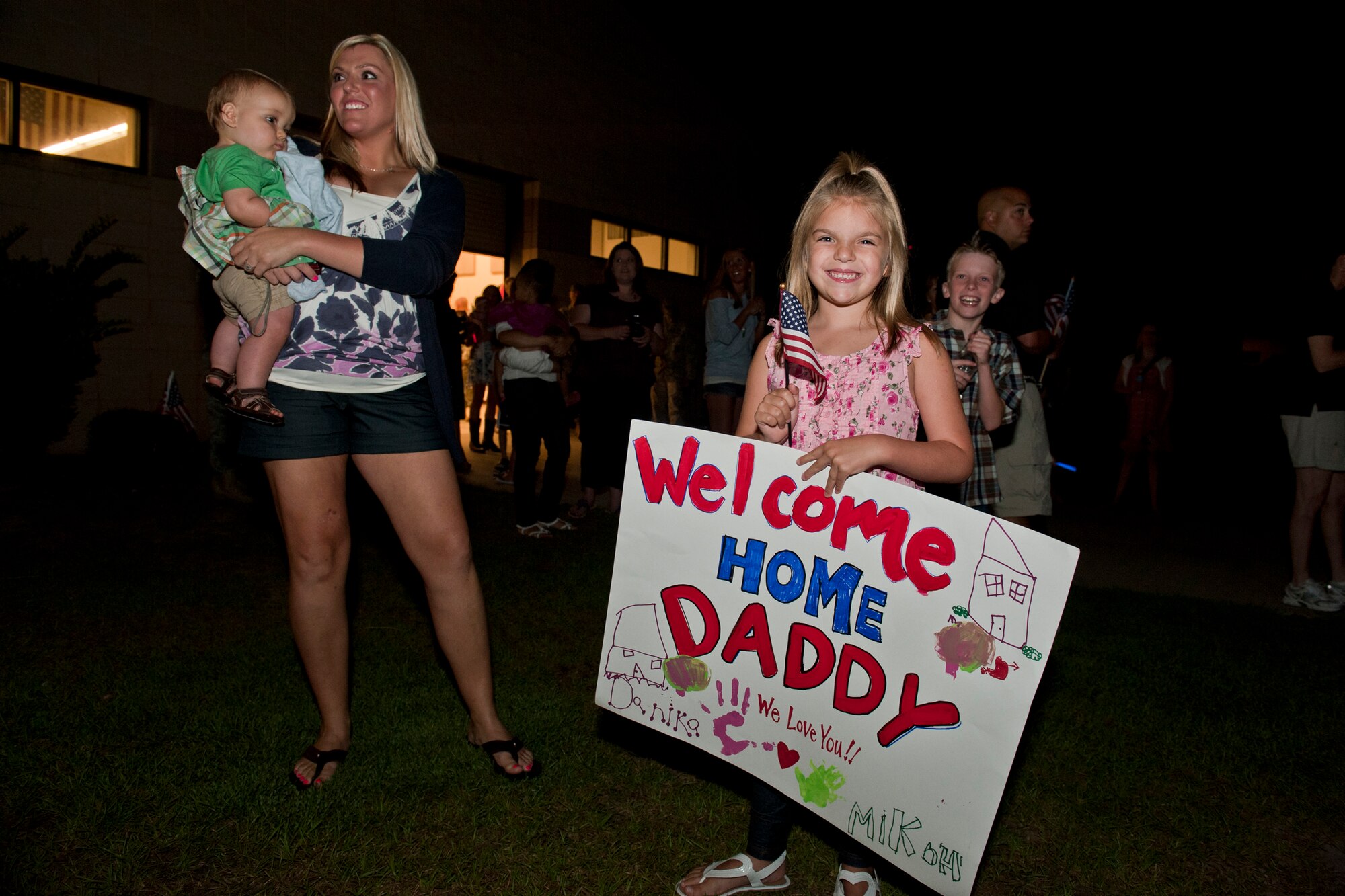 Danika, daughter of Senior Airman David Watson, 823rd Base Defense Squadron, shows off a welcome home sign in anticipation for her father’s return June 26, 2011, at Moody Air Force Base, Ga. Friends and family gathered around 2 a.m. to welcome their loved ones after a six-month deployment to Afghanistan. (U.S. Air Force photo by Staff Sgt. Jamal D. Sutter/Released)