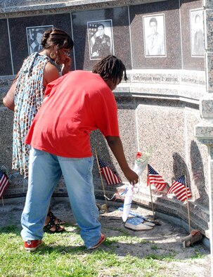 PATRICK AIR FORCE BASE, Fla.- Shyrl Johnson, wife of Staff Sgt. Kevin J. Johnson, and their son Nicholas Johnson lay a flower under Sergeant Johnson's portrait. "Coming back to celebrate their life to me is awesome," said Ms. Johnson. Sergeant Johnson lost his life 15 years ago when a fuel truck exploded in front of the Khobar Towers. (U.S. Air Force photo/Airman First Class Natasha Dowridge) 
