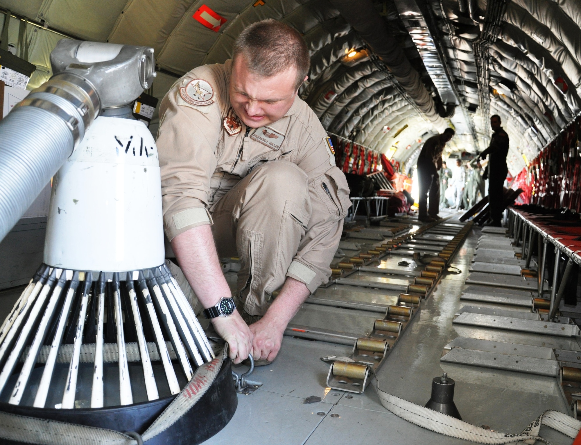 Adjusting straps to secure a drogue to the cargo bay of a KC-135 Stratotanker, Staff Sgt. Randy Miller helps prepare the plane at Moses Lake, Wash., for a historic mission over the Arctic Circle and through Russia from Washington state to the Transit Center at Manas, Kyrgyzstan, on June 21, 2011.  Sergeant Miller is a boom operator assigned to the 92nd Air Refueling Squadron at Fairchild Air Force Base, Wash. The tanker crew flew over the North Pole for the first time June 21 to 22, 2011, as part of an “iron swap” mission along a new, more efficient route from Washington state to Kyrgyzstan.  (U.S. Air Force Photo/Capt. Kathleen Ferrero)