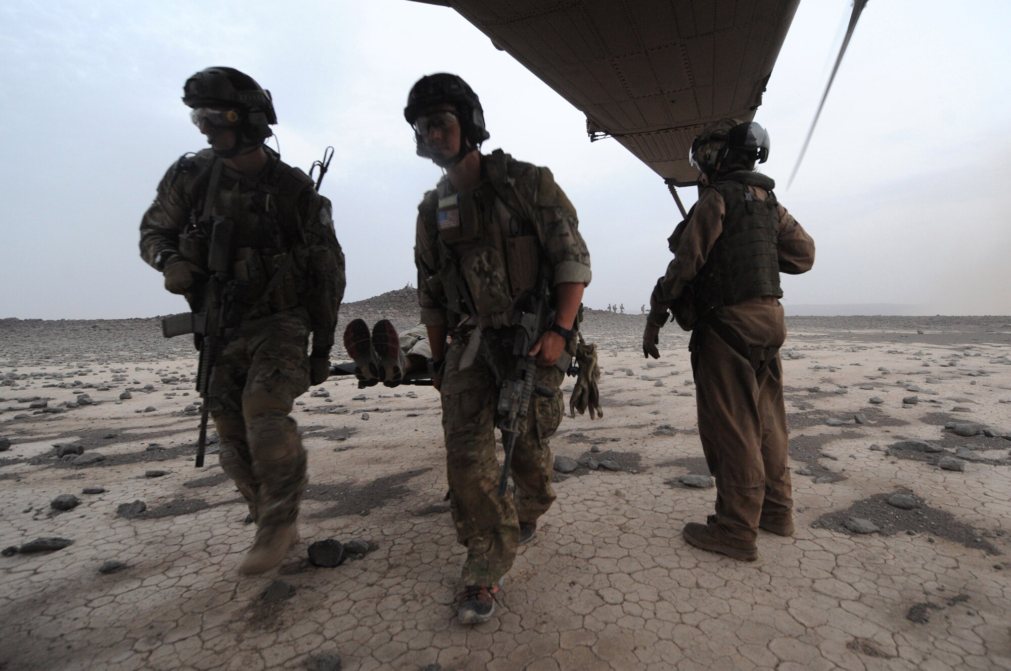 DJIBOUTI, Africa -- U.S. Air Force pararescuemen carry a  victim of a simulated aircraft crash onto a U.S. Marine Corps MH-53 helicopter in the Grand Bara desert, Djibouti, during a personnel recovery exercise June 16.  The scenario was part of a joint training exercise involving all branches of the U.S. military stationed at Camp Lemonnier, Djibouti. (U.S. Air Force photo by Staff Sgt. Austin M. May)
 