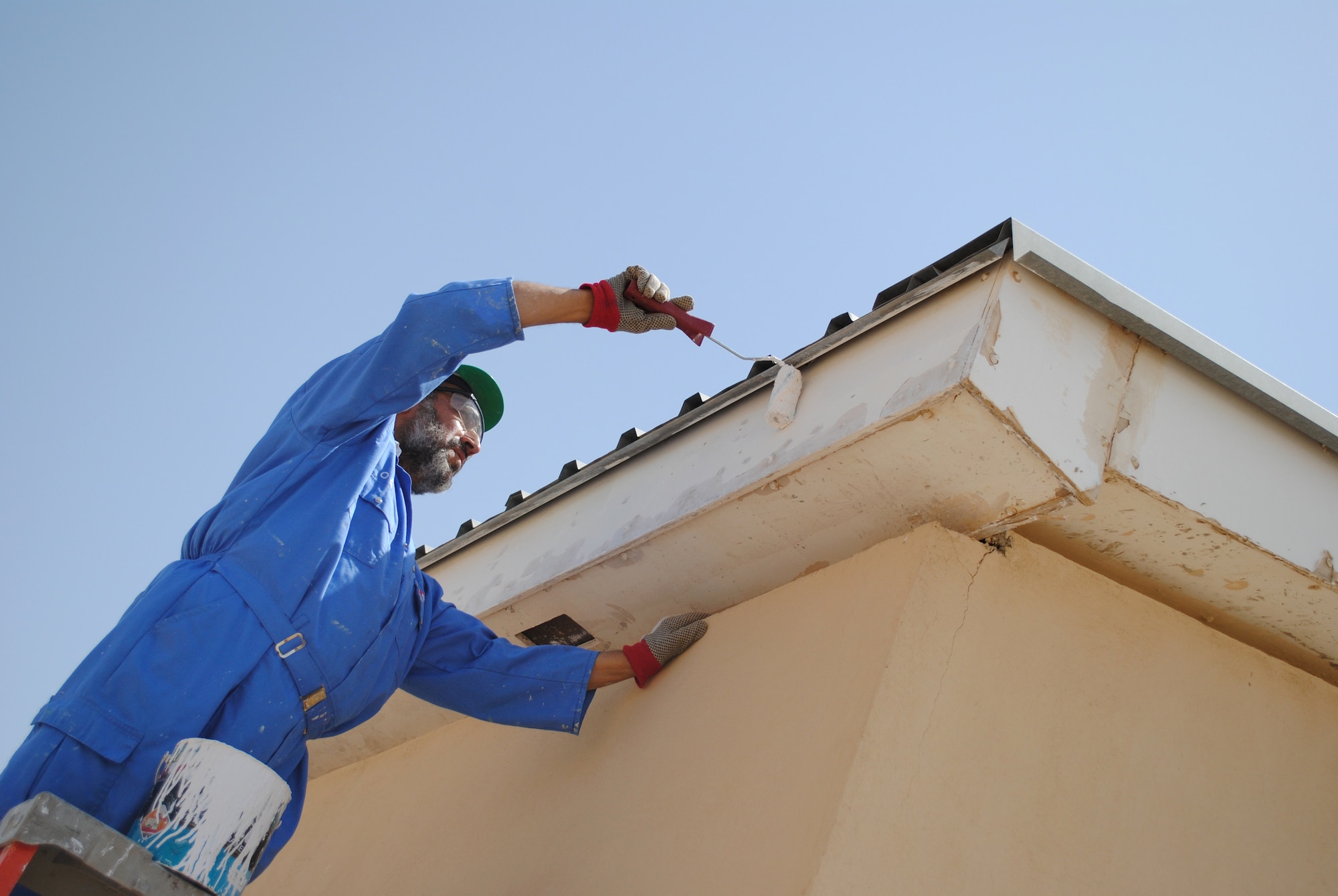 A worker paints the eaves of a building maintained by Afghans at Camp Hero, on Jun. 25, 2011, in Kandahar, Kandahar province, Afghanistan.  NATO Training Mission-Afghanistan's Infrastructure Training and Advisory Group plans to turn 17 buildings over to Afghan control on Camp Hero.  Each Afghan-maintained building will display a painted Afghan flag.  (U.S. Air Force photo by Tech Sgt. Adrienne Brammer)
