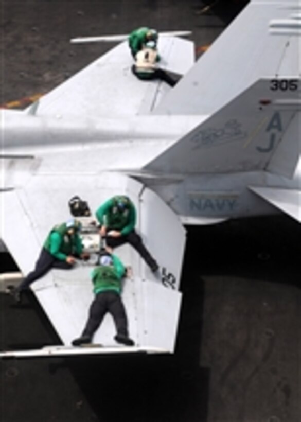 Sailors assigned to Strike Fighter Squadron 15 perform maintenance on an F/A-18C Hornet aboard the aircraft carrier USS George H.W. Bush (CVN 77) in the Gulf of Aden on June 21, 2011.  The George H.W. Bush is deployed supporting maritime security operations and theater security cooperation efforts in the U.S. 5th Fleet area of responsibility on its first overseas deployment.  