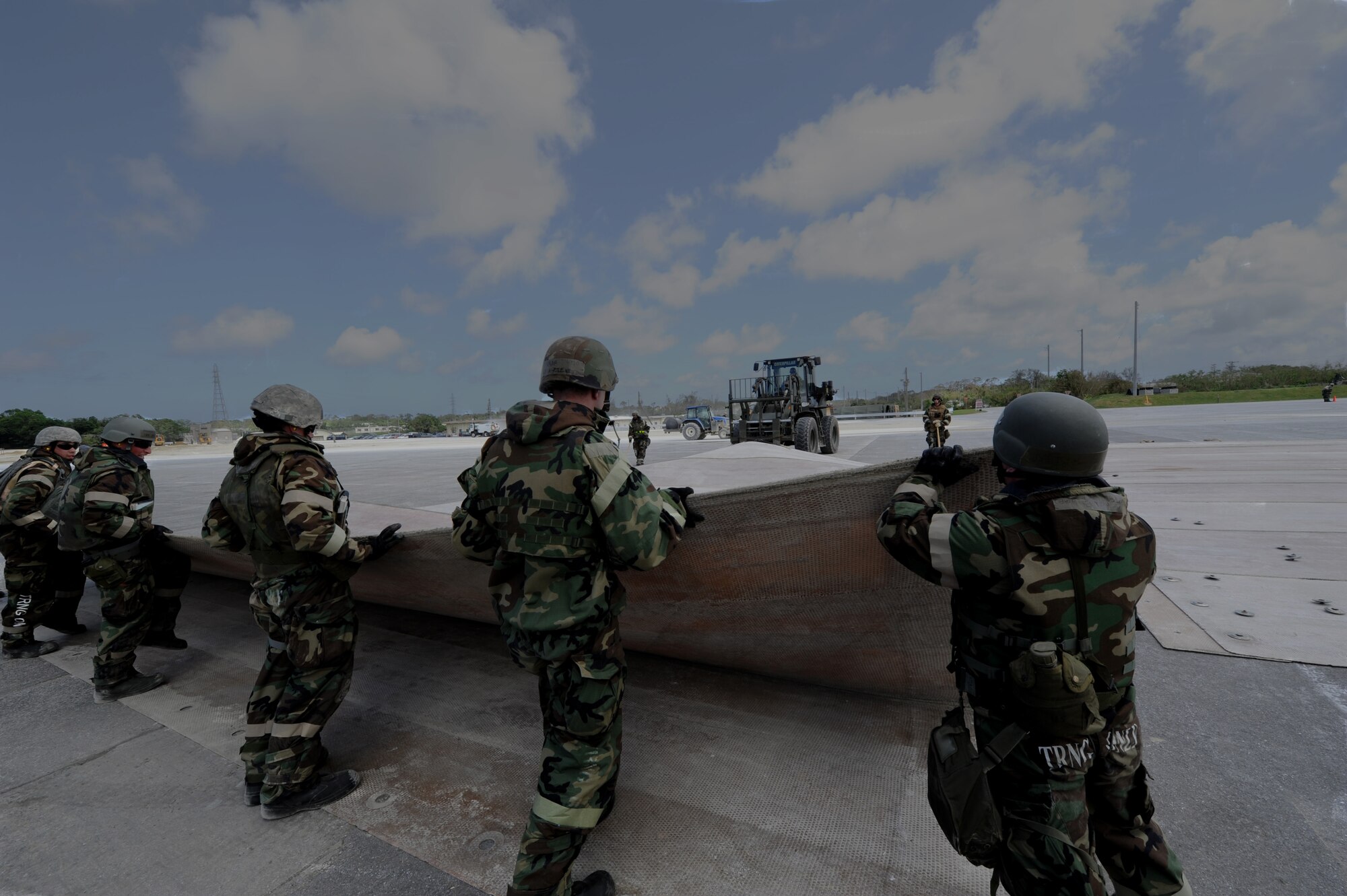 Civil engineers fold a fiberglass mat which is used for crater repair during Silver Flag 11-06 at Kadena Air Base, Japan, June 28. Silver Flag is a week-long exercise where Airmen train on how to open, establish and sustain a forward-operating base before they deploy to real-world operations. (U.S. Air Force photo/Airman 1st Class Jarvie Z. Wallace)