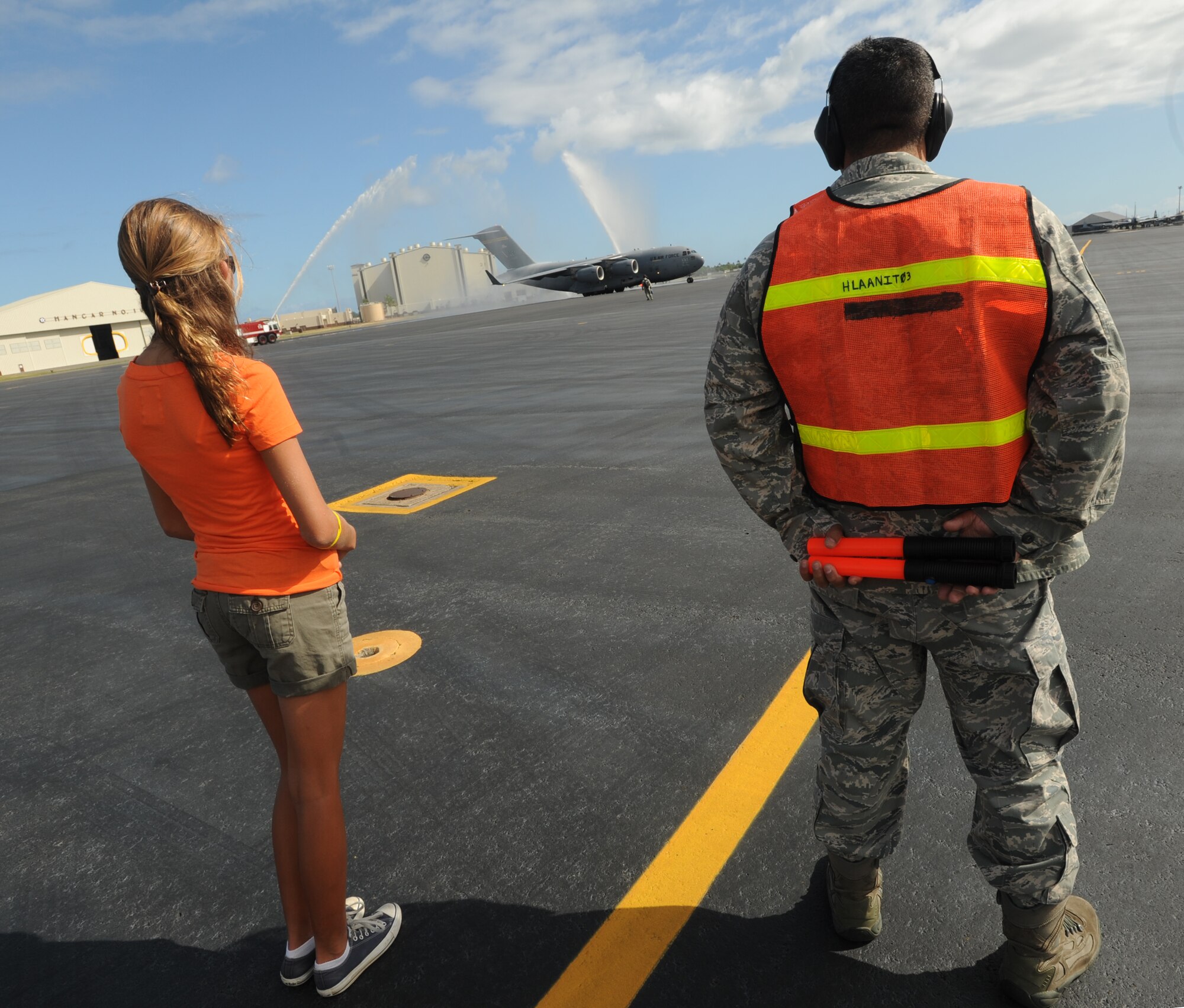 Col. Jeffrey Morgan, 15th Operations Group commander, taxis through a "rainbow" of water as his daughter waits to marshal him in for his final flight in a 535th Airlift Squadron C-17 Globemaster III June 23. Colonel Morgan and his family are making a permanent change of station to the Pentagon in Washington D.C. (U.S. Air Force photo/Senior Airman Lauren Main)