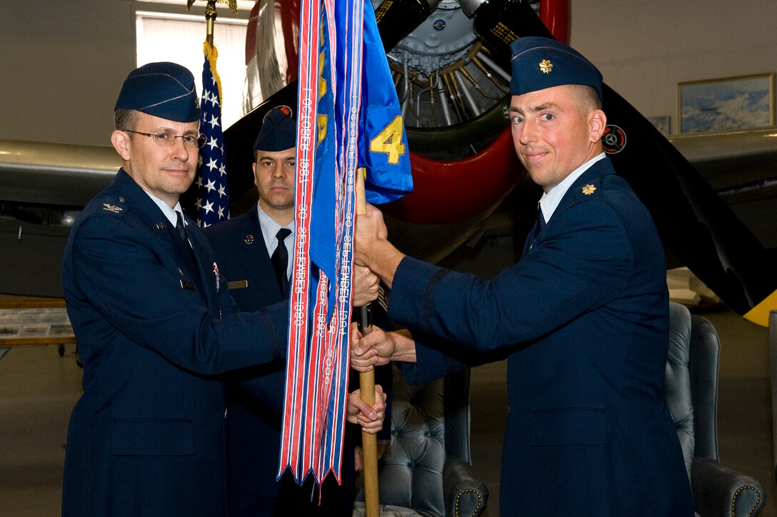 Col. Brian Norman, Air Force Manpower Agency commander, passes the squadron colors to Maj. Nathan Tarkowski, incoming 4th Manpower Requirements Squadron commander, during the 4th MRS change of command ceremony June 24 at the Peterson Air Force Base Museum Hangar. Major Tarkowski assumes command from Lt. Col. Ernest Wearren. The 4th MRS is the operational arm of the management engineering program for the Air Force and determines manpower requirements for Air Force units. (U.S. Air Force photo/Craig Denton)