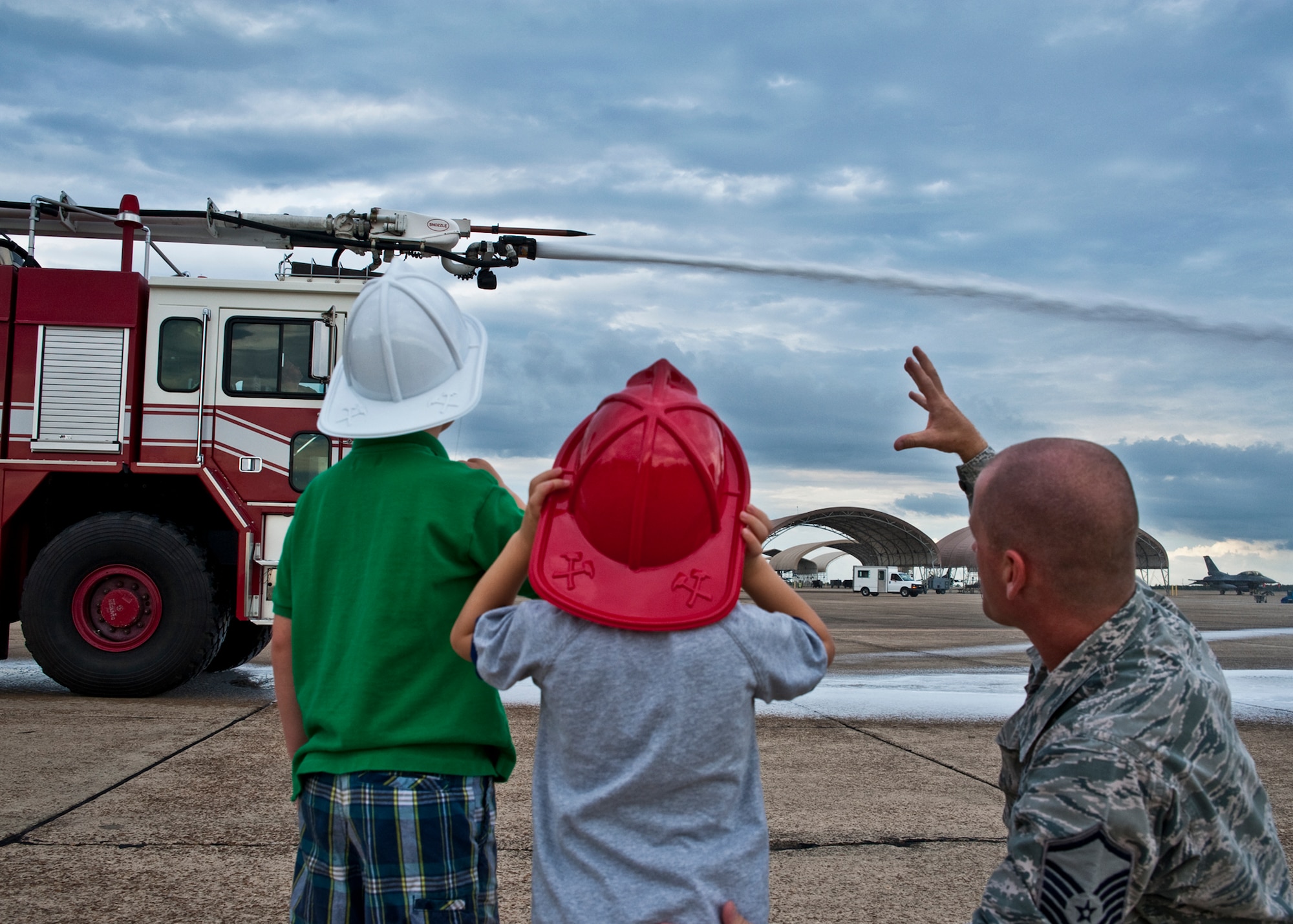 Six-year-old Andy Hitt and his 3-year-old brother Alex, sons of Senior Master Sgt. Kevin Hitt, Air Armament Center, watch as the water cannon hoses down the flightline June 24 at Eglin Air Force Base, Fla.  Andy was recognized by the base fire department for saving his brother Alex from drowning in March.  As part of his recognition, he was made an honorary firefighter, sat in a fire engine and fired the water cannon as well.  (U.S. Air Force photo/Samuel King Jr.)