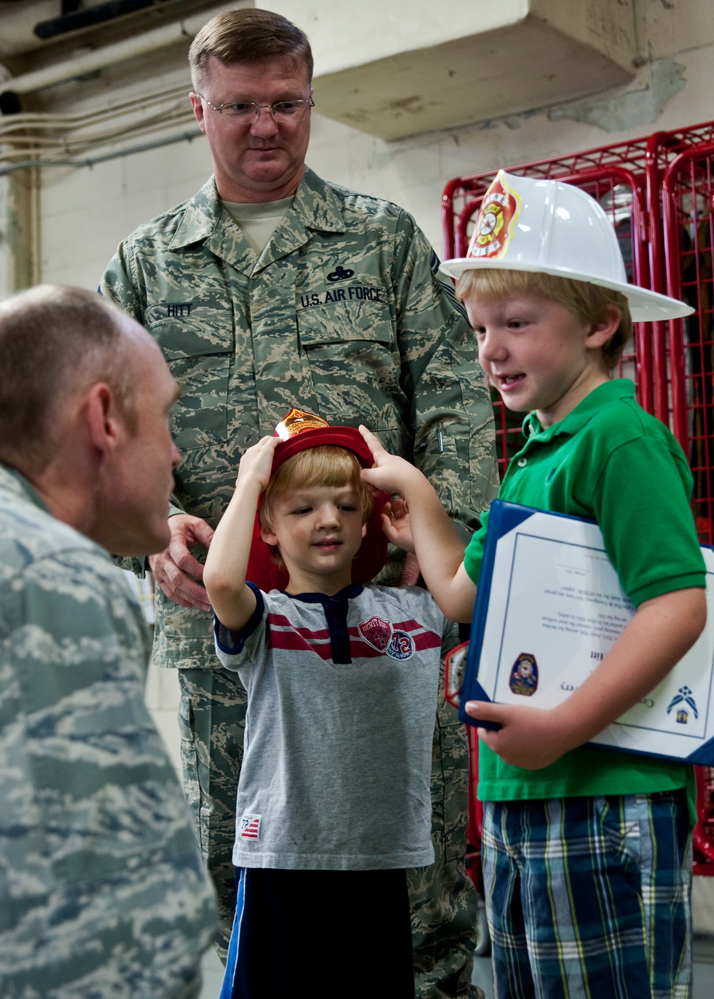 Six-year-old Andy Hitt, son of Senior Master Sgt. Kevin Hitt, Air Armament Center, tells Col. Bill Porter, 96th Air Base Wing vice commander, about his heroic rescue June 24 at Eglin Air Force Base, Fla.  Andy was recognized by the base fire department for saving his 3-year-old brother Alex (also pictured) from drowning in March.  As part of his recognition, he was made an honorary firefighter, sat in a fire engine and fired the water cannon.  (U.S. Air Force photo/Samuel King Jr.)