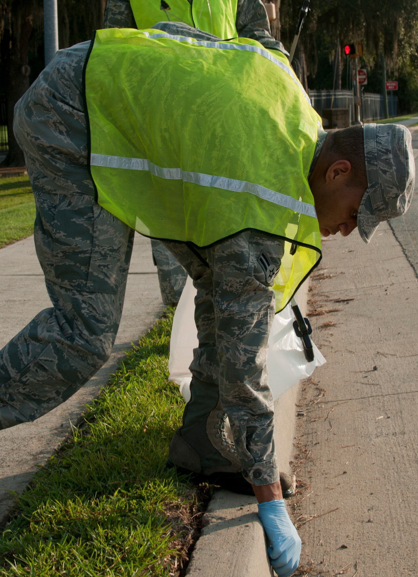 U.S. Air Force Airman 1st Class Marc Lawson, 23rd Wing Command Post emergency actions controller, removes trash from the curb during a Pride Patrol at Moody Air Force Base, Ga., June 28, 2011. A group of about 15 volunteers from the 23rd WG staff agencies walked the sidewalk in front of the base to clean up trash along their way. (U.S. Air Force photo by Senior Airman Benjamin Wiseman/Released)