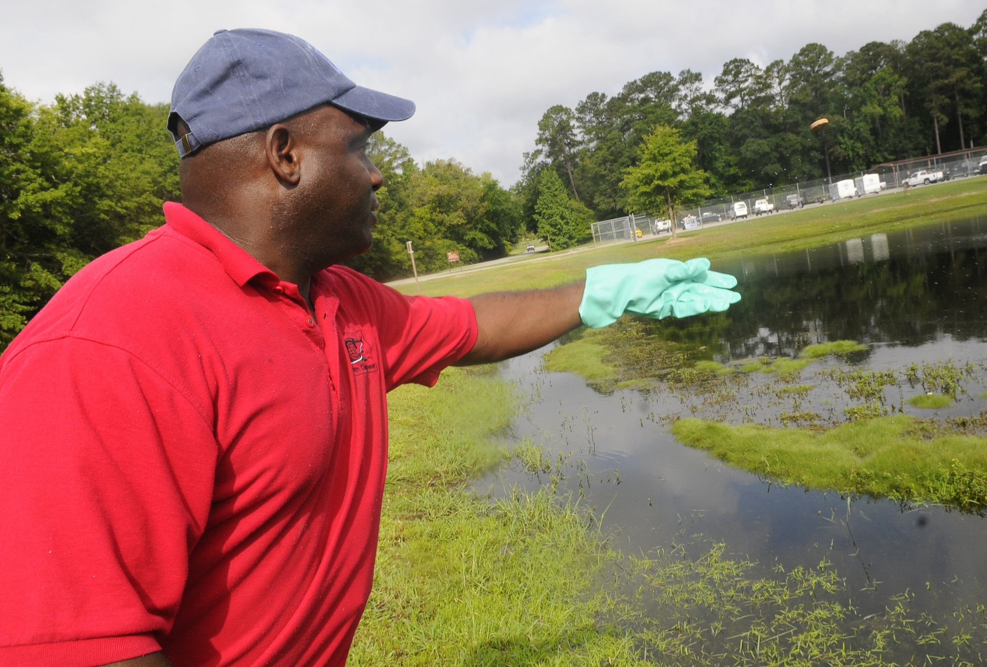Mansur Cooper, pest control technician, tosses a larvacide donut in to a pond to kill mosquito larvae. U. S. Air Force photo by Sue Sapp
