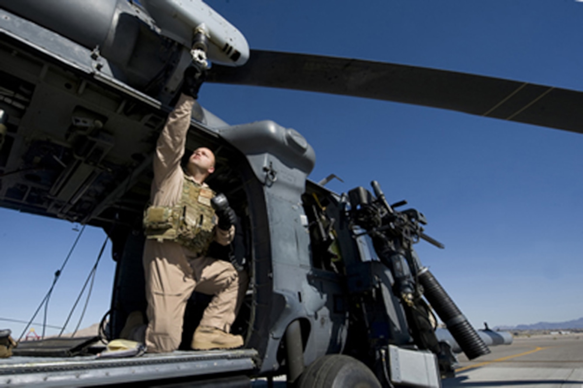 U.S. Air Force Staff Sgt. David Mullikin grabs the hoist of an HH-60 Pavehawk, Nellis Air Force Base, Nev., June 23. Sergeant Mullikin is a flight engineer assigned to the 66th Rescue Squadron.  (U.S Air Force photo by Senior Airman Stephanie Rubi / Released) 
