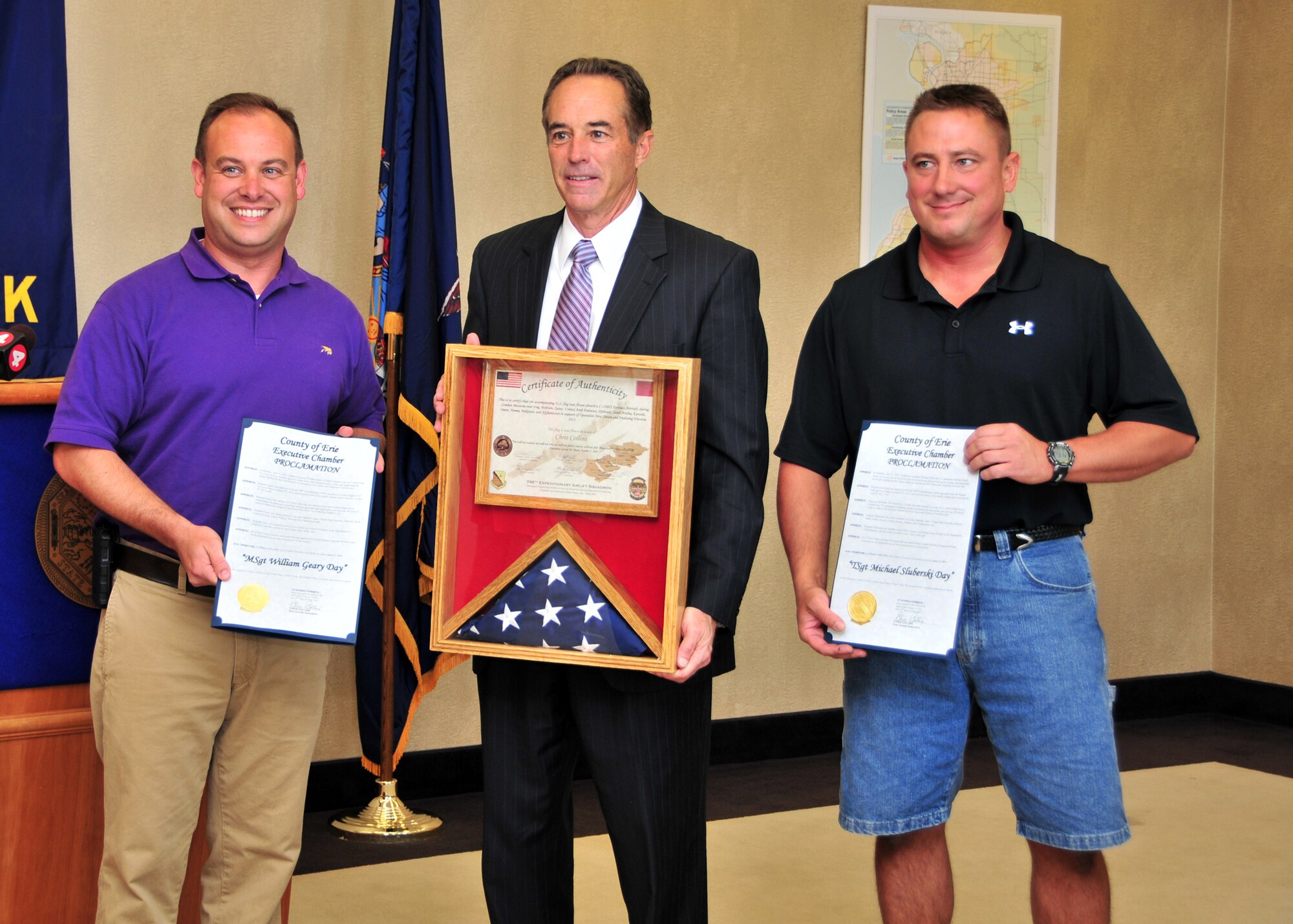 Master Sgt. Bill Geary (left) and Tech. Sgt. Mike Sluberski, of the 328th Airlift Squadron present Erie County Executive Chris Collins (center) folded flags that flew in combat over southwest Asia June 27, 2011 Buffalo, NY. The flags were presented at the Edward Rath Building as thanks for their employers' support during the Sergeants' deployment. (U.S. Air Force photo by Staff Sgt. Joseph McKee)