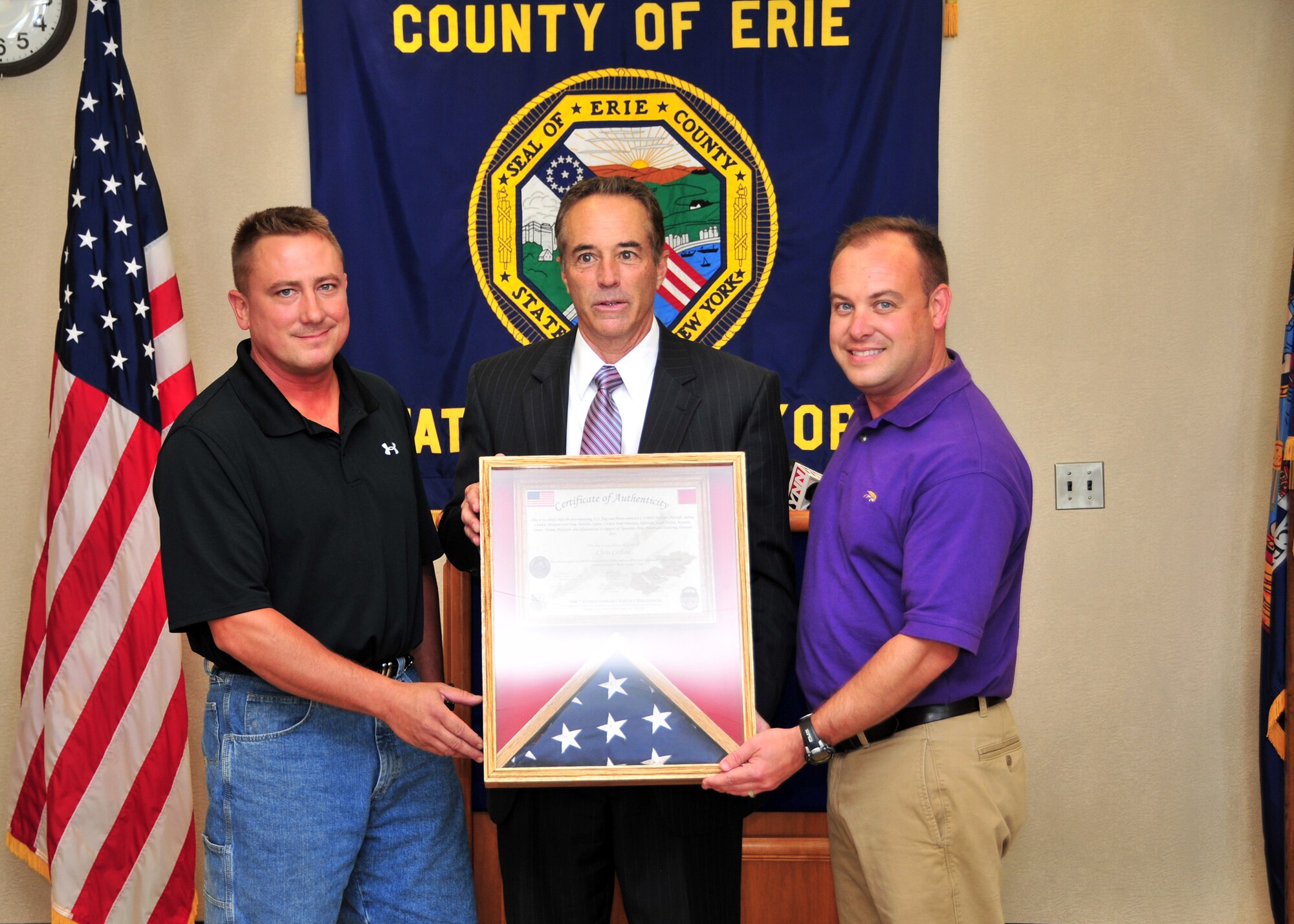 Tech. Sgt. Mike Sluberski (left) and Master Sgt. Bill Geary, of the 328th Airlift Squadron present Erie County Executive Chris Collins (center) folded flags that flew in combat over southwest Asia June 27, 2011 Buffalo, NY. The flags were presented at the Edward Rath Building as thanks for their employers' support during the Sergeants' deployment. (U.S. Air Force photo by Staff Sgt. Joseph McKee)
