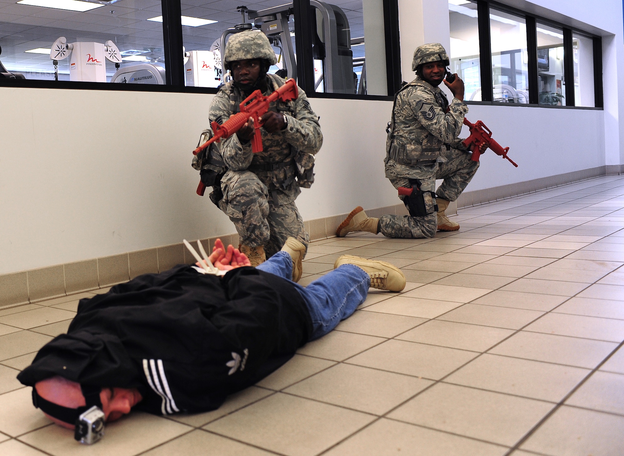 U.S. Air Force Master Sgt. Robert Murdock, 23rd Security Forces Squadron flight chief (right), reports an update to the unit control center while Staff Sgt. Kendrick Brooks, 23rd SFS patrolman, guards a simulated gunman during an active shooter exercise at Moody Air Force Base, Ga., June 24, 2011.  The gunman was played by Tech. Sgt. Clint Ellis, 23rd SFS plans and programs NCO in-charge. (U.S. Air Force photo by Senior Airman Stephanie Mancha/Released)