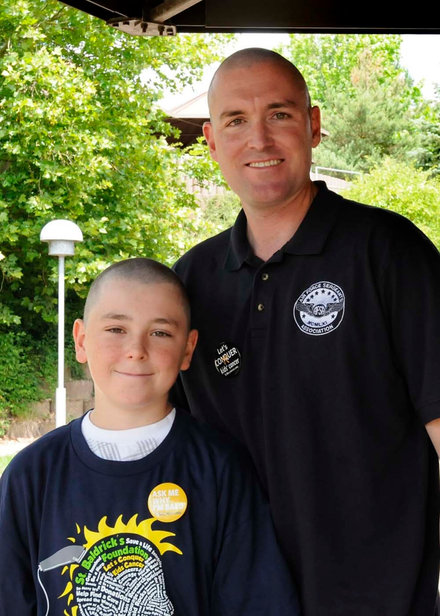 U.S. Air Force Senior Master Sgt. Don Gurganus, American Forces Network Ramstein superintendent, and son, Logan Gurganus, 12, pose for a picture after having their heads shaved in participation of the second annual St. Baldricks event on Ramstein Air Base, Germany, June 26, 2011. The St. Baldricks Foundation is an organization that tasks volunteers with getting sponsored to have their heads shaved as a demonstration of their camaraderie to children that have been diagnosed with cancer. (U.S. Air Force photo by Airman 1st Class Kendra Alba)
