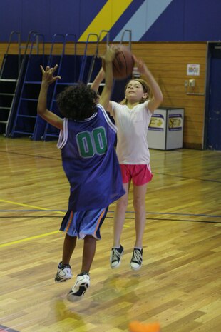 Shion B. Fleming, 8, blocks Kailey M. Crochet's, 10, jump shot in a scrimmage game during the Marine Corps Community Services  Commands Sports Camp here at the IronWorks Gym sports courts here June 28. Soccer, dodgeball, and bowling are some of the other camps that are offered during the summer months to station residents' children. Marines are also invited to come out and help give back to the community by volunteering as coaches during this time.