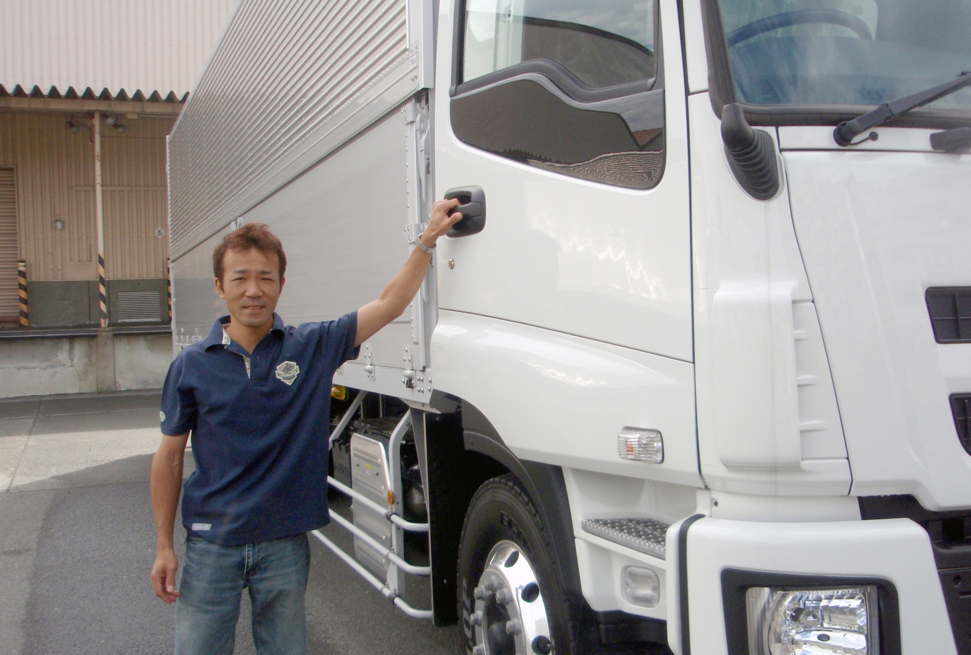 YOKOTA AIR BASE, Japan -- Prior to beginning his work day, Tokyo native, Masaaki Tanaka, a heavy vehicle driver for the Army and Air Force Exchange Service, stands next to his  truck June 23 at the Exchange's Japan Distribution Center located on Yokota Air Base. Tanaka, who was recently named as the Exchange's Pacific Region Driver of the Year for 2010, will be officially receiving the award during a November ceremony at the Yokota Air Base Distribution Center.  (Photo courtesy of Chika Nakajima, Exchange Japan Distribution Center)