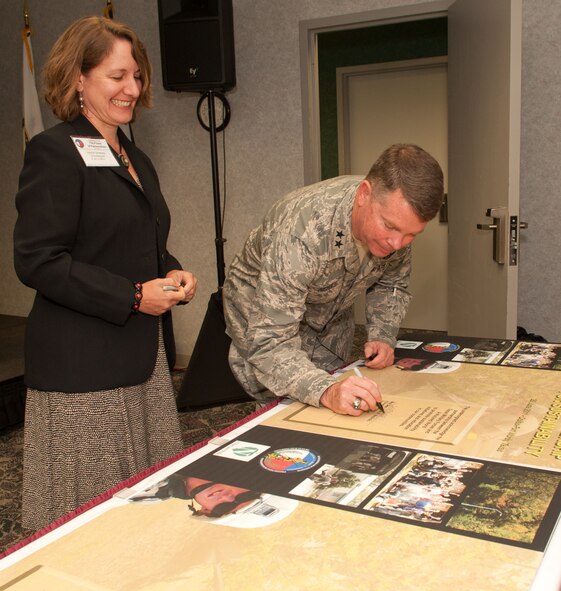 Maj. Gen. John Nichols signs environmental posters with Ms. Denise Rayborn Wickerson, signing for the executive director of A Nurtured World, during the Power of Partnerships Sustainability Conference Signing Ceremony at the American Airlines Training Center, Fort Worth, Texas, June 29, 2011. The signing of the posters signify the partnership between TXMF and A Nurtured World, an environmental organization. (U.S. Air Force photo by Senior Master Sgt. Elizabeth Gilbert)