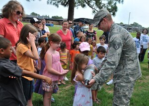 Children wait in line to feel the weight of a blank explosive round during an Explosive Ordnace Disposal demonstration by Staff Sgt. John Morrison, an EOD craftsman from the 628th Civil Engineer Squadron, June 29 on Joint Base Charleston - Air Base.  More than 50 children, teenagers and their parents participated in the demonstration, learning about improvised explosive devises, land mines and the equipment used to disarm them. (U.S. Air Force photo /Airman 1st Class Jared Trimarchi)
