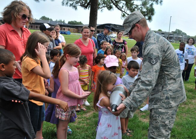 Children wait in line to feel the weight of a blank explosive round during an Explosive Ordnace Disposal demonstration by Staff Sgt. John Morrison, an EOD craftsman from the 628th Civil Engineer Squadron, June 29 on Joint Base Charleston - Air Base.  More than 50 children, teenagers and their parents participated in the demonstration, learning about improvised explosive devises, land mines and the equipment used to disarm them. (U.S. Air Force photo /Airman 1st Class Jared Trimarchi)