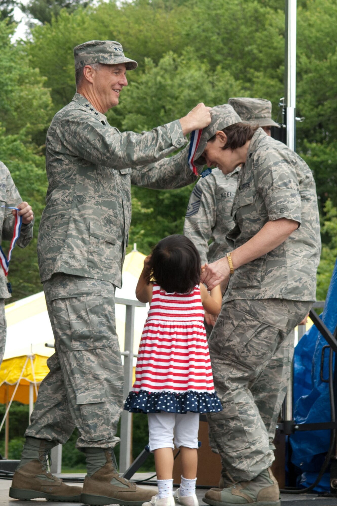 HANSCOM AIR FORCE BASE, Mass. – Lt. Gen. Ted Bowlds (left), Electronic Systems Center commander, presents a medallion to Lt. Col. Tamara Schwartz, along with her daughter, during Heroes Homecoming at Memorial Park June 24. More than 30 military men and women who have returned home from deployment within the last six months were honored during the pep rally-style event. (U.S. Air Force photo by Rick Berry)