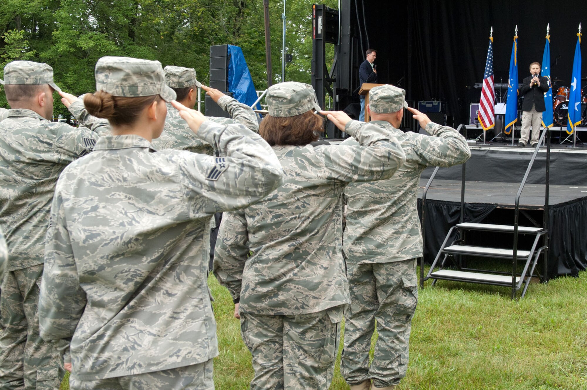 HANSCOM AIR FORCE BASE, Mass. – Heroes salute as Joey Grieve sings the national anthem during Heroes Homecoming at Memorial Park 24. Base senior leaders, a Medal of Honor recipient two former New England Patriots players and the base community officially welcomed home 30 Airmen who have returned from deployment within the last six months. (U.S. Air Force by Rick Berry)