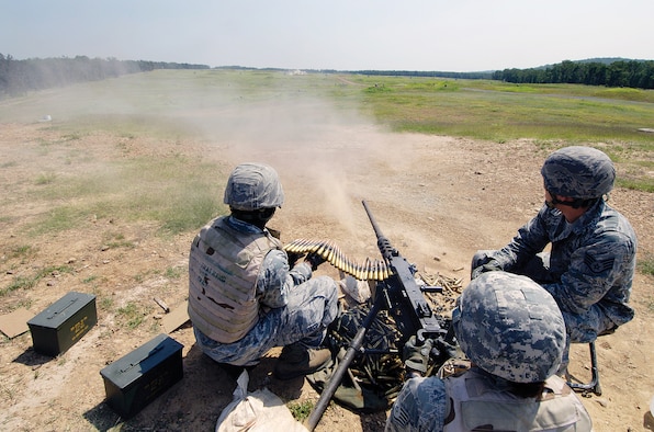Staff Sgt. Andrea Byrd watches her firing precision by the dirt kicked up meters down range as she fires .50-caliber rounds from an M2 machine gun June 9 at the Camp Gruber Training Center in eastern Oklahoma.  Airman 1st Class Justin Simmons feeds belts of ammunition to the weapon that can rip through 100 rounds in about 15 seconds. Tinker 72nd Security Forces Combat Arms instructor Staff Sgt. David Tuscany watches her aim.  The annual qualifying firing was a victory for the Airman who was injured when an M2 malfunctioned during 2009 training in Iraq. (Air Force photos by Margo Wright)